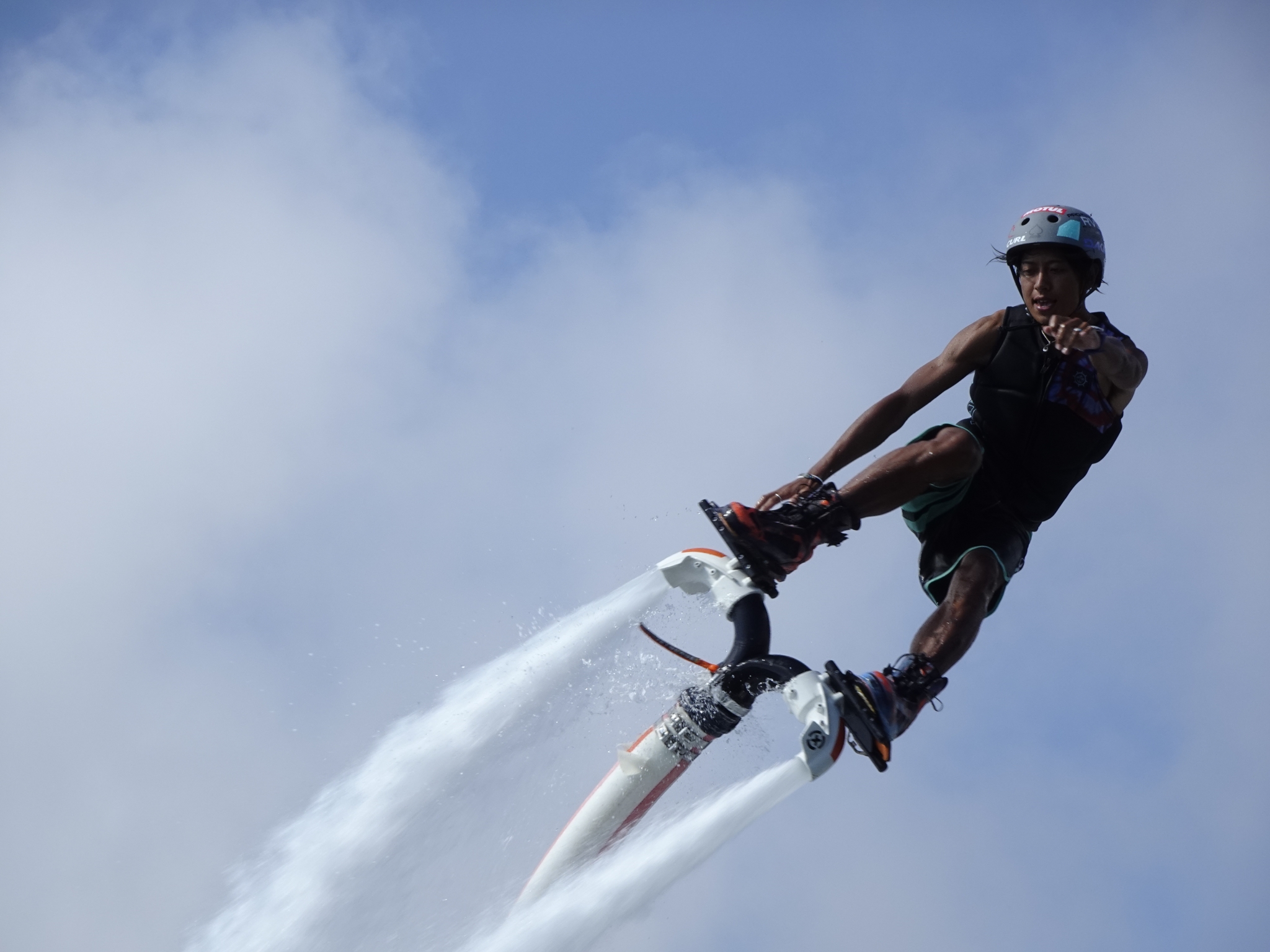 Man riding a flyboard high in the air, pointing towards the camera