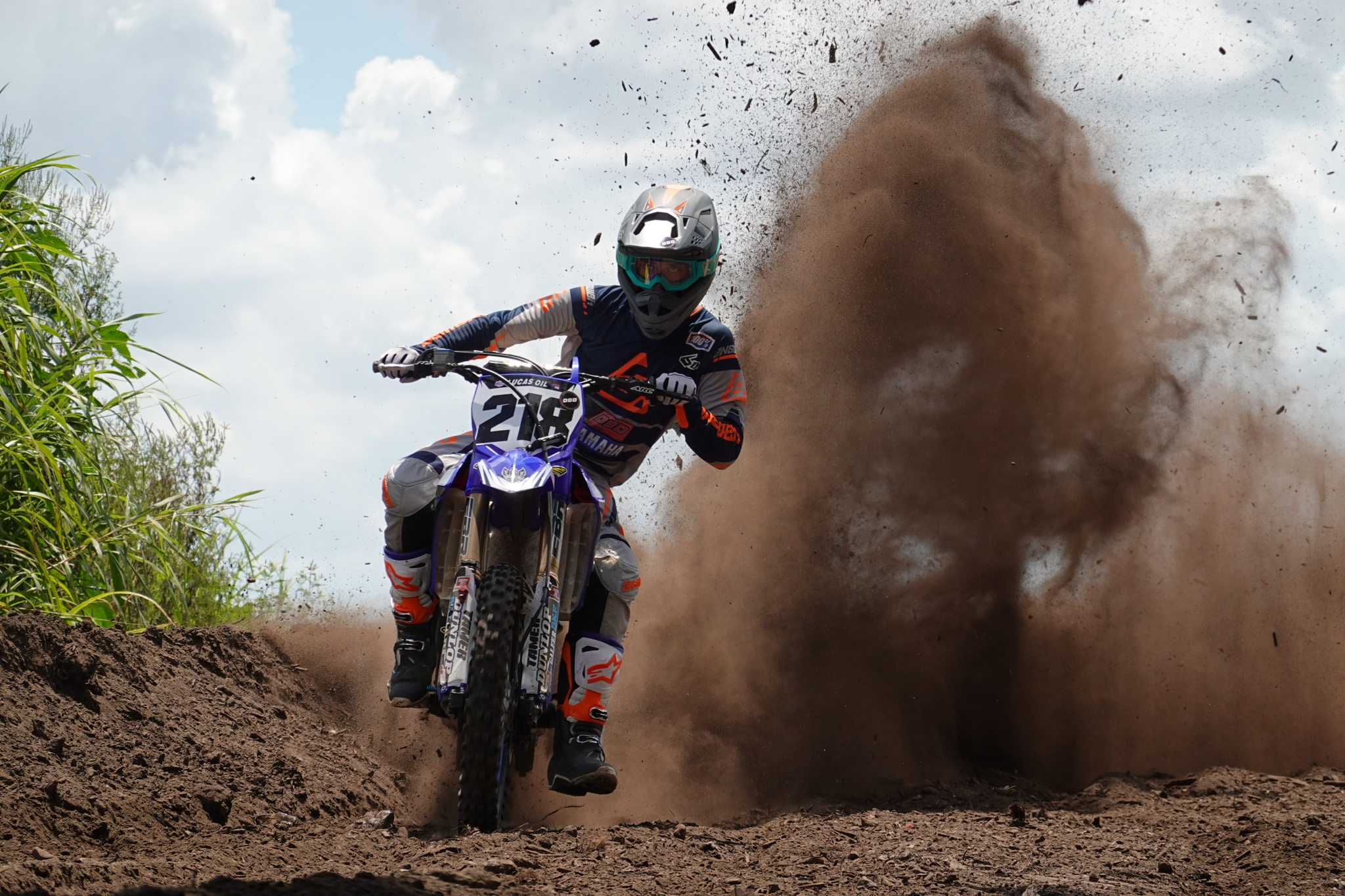 Motorcyclist riding through dirt, churning up a dust cloud behind the motorbike