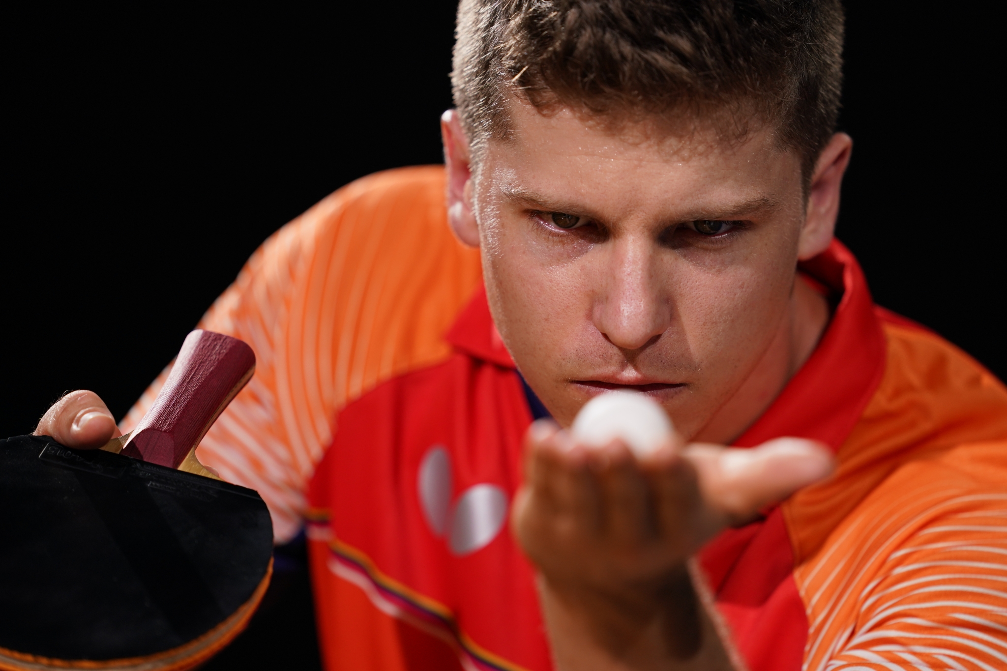 Close-up of table tennis player looking at the white ball in his palm
