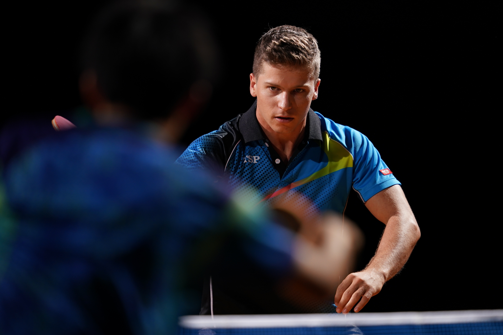 Table tennis player competing against an opponent in bokeh foreground