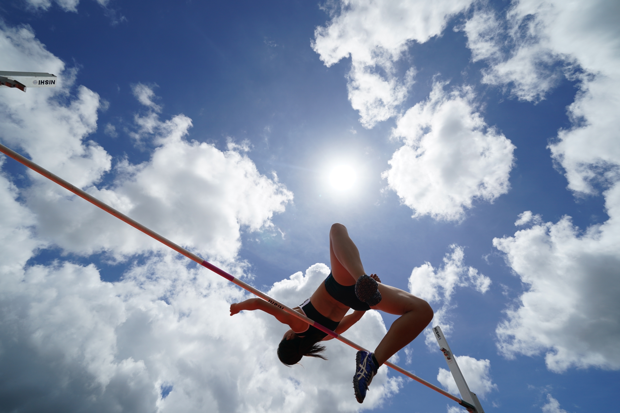 Female athlete doing the high jump against a blue sky