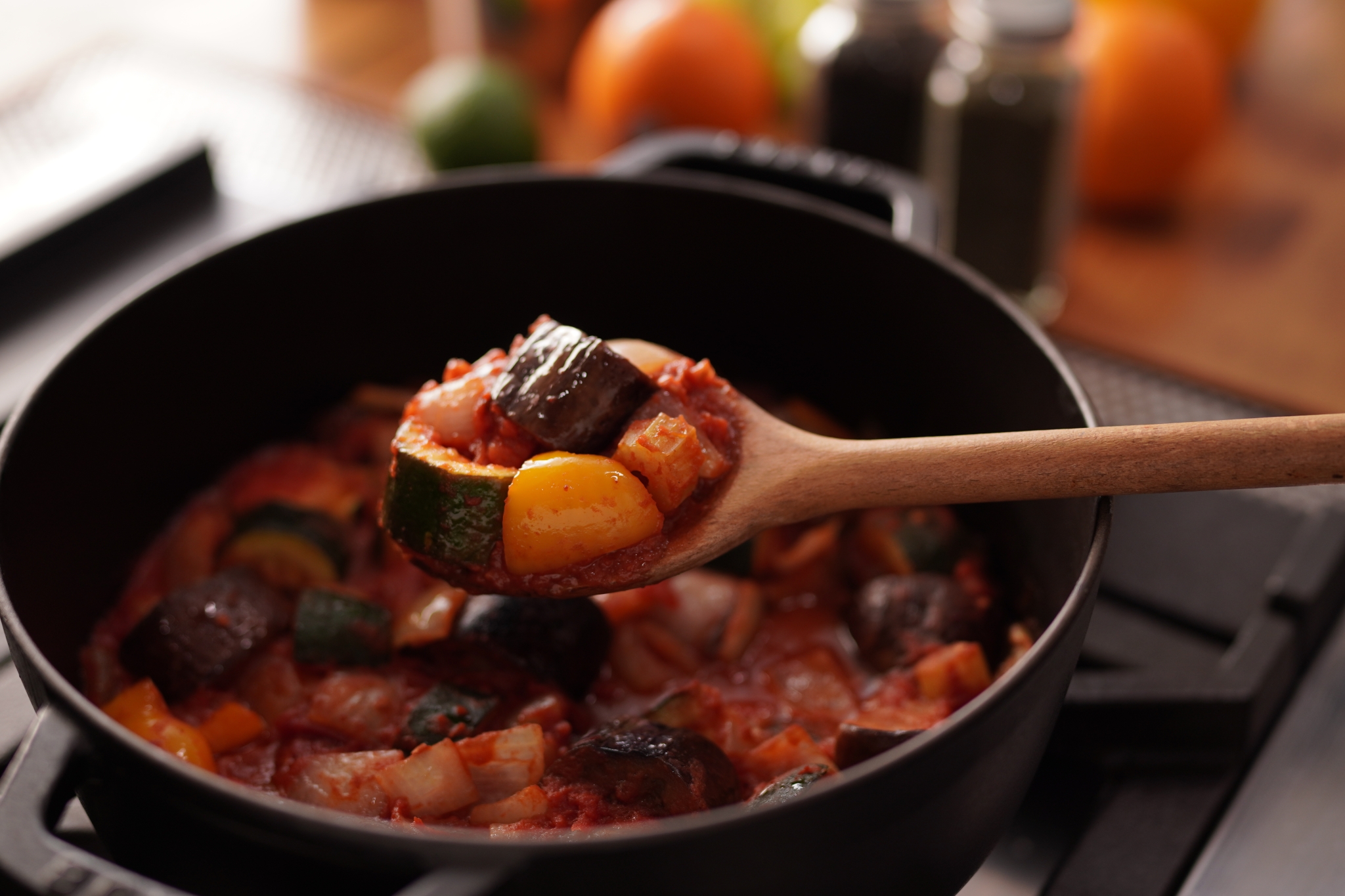 Ratatouille in a saucepan with a wooden spoon holding a spoonful