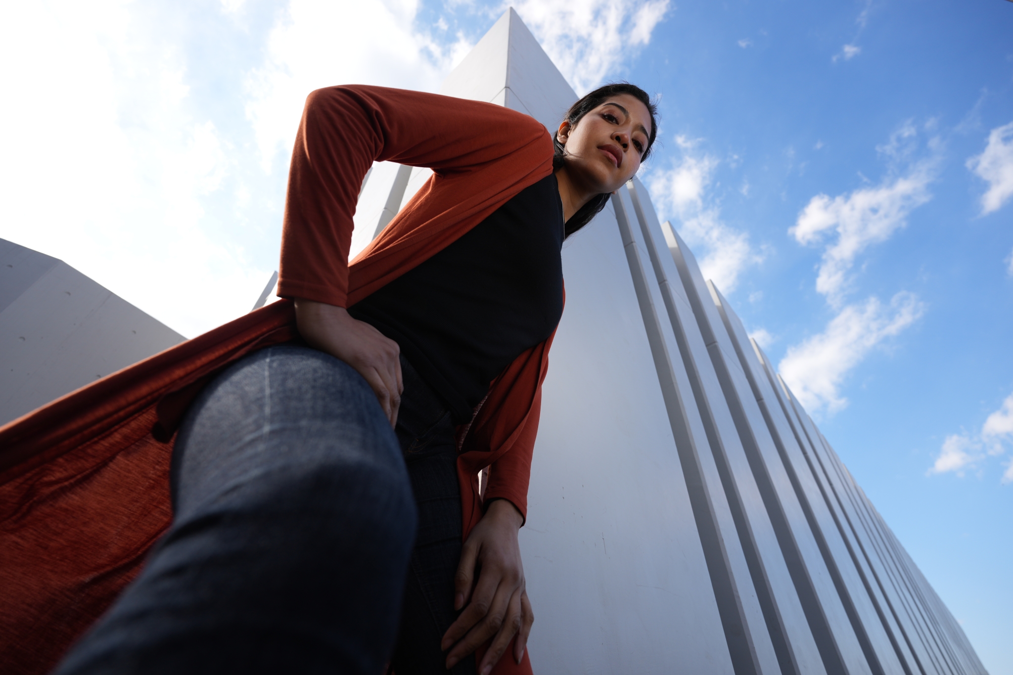 Female model looking down toward camera with a skyscraper in the background