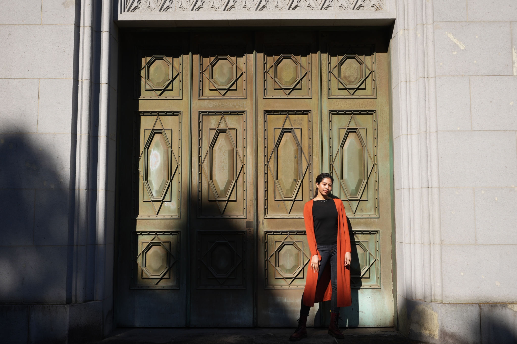 Female model standing next to a large wooden door