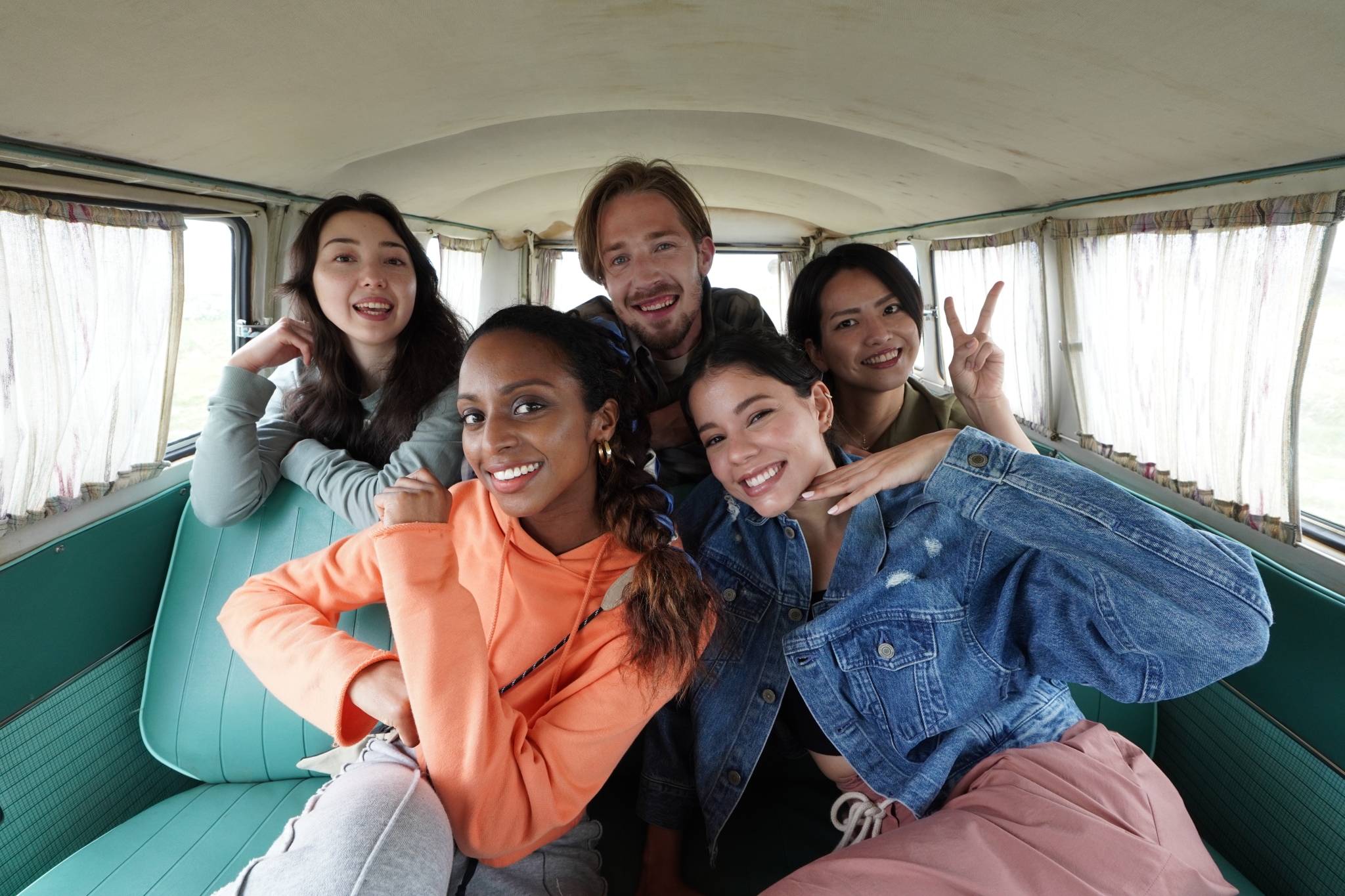 Group of five people posing for a photo inside a camper van