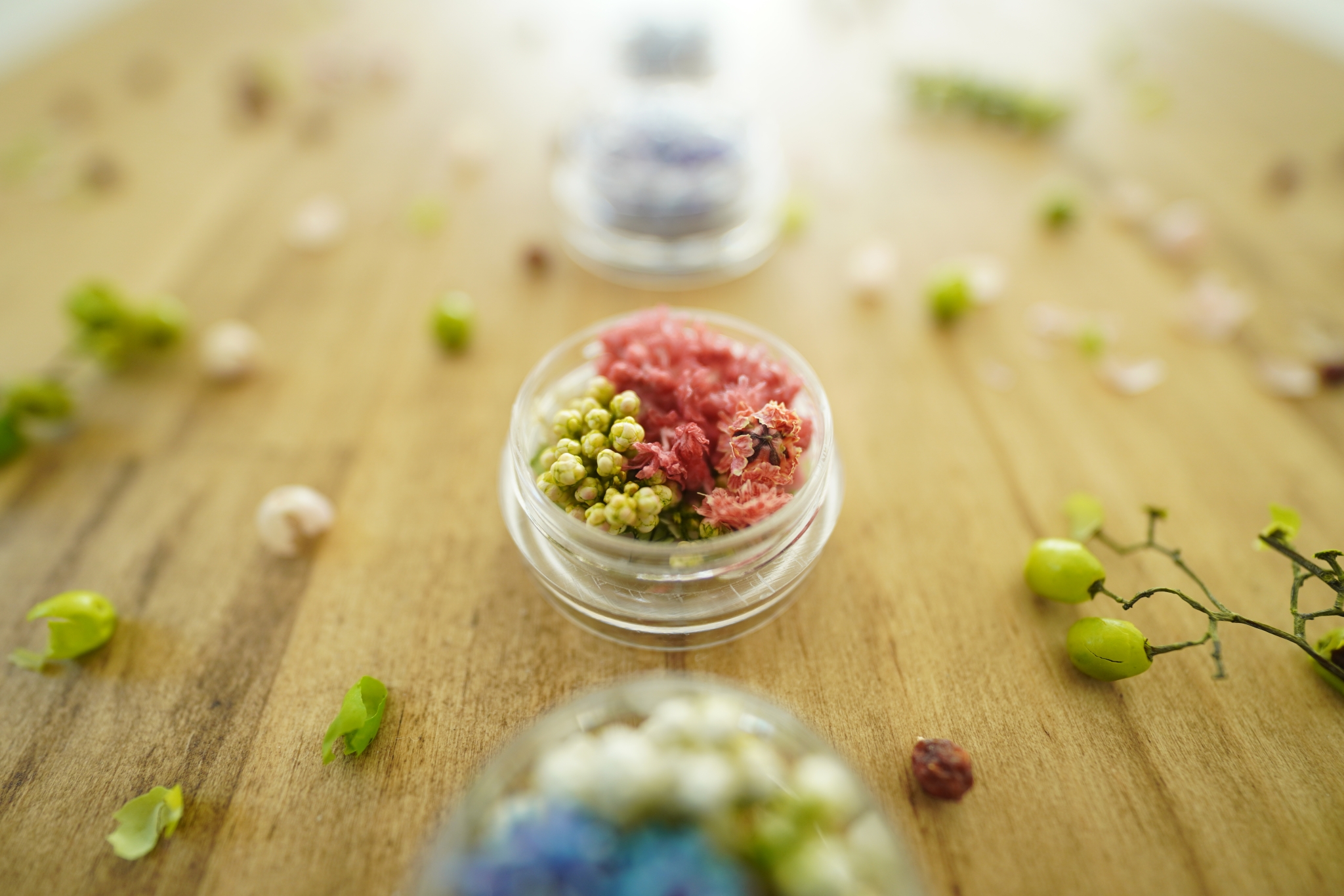 Decorative berries and flowers in a small glass vase with bokeh foreground and background