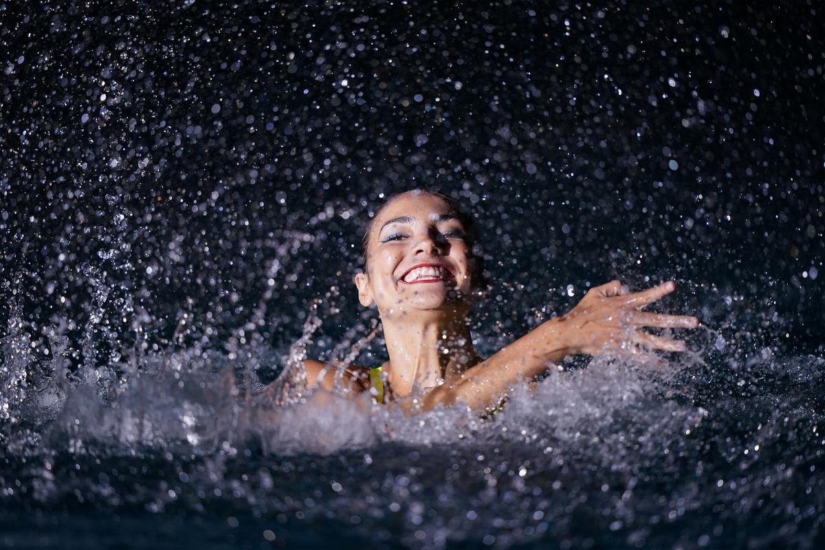 Synchronised swimmer smiling and splashing
