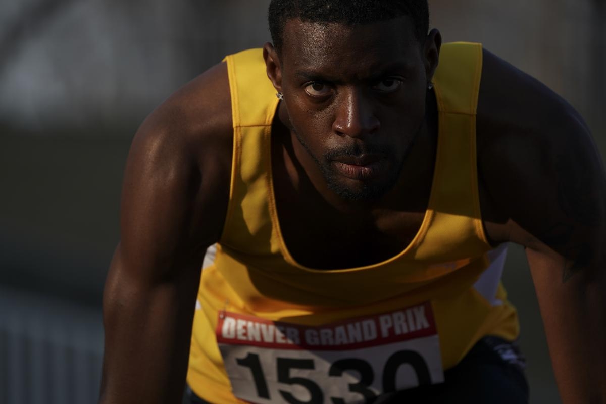 Portrait of male runner bent over about to start a race, a look of concentration on his face