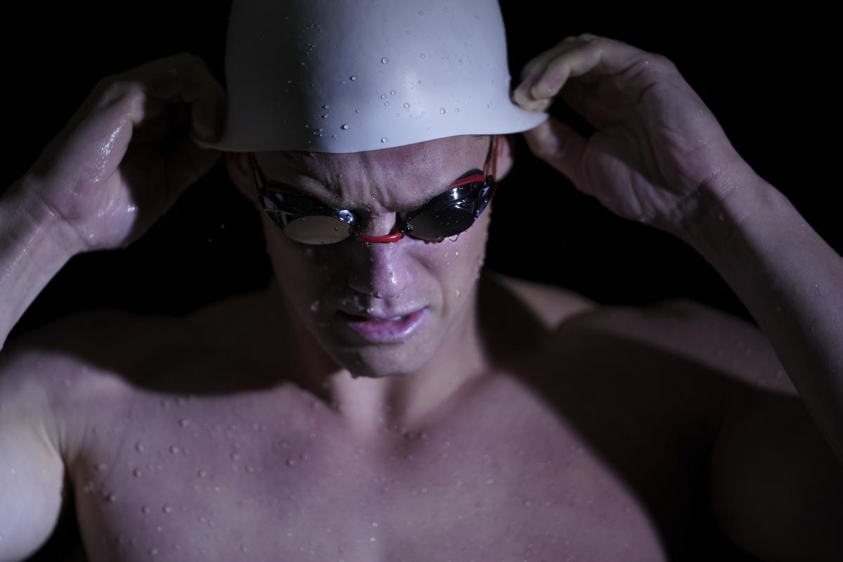 Portrait of male swimmer adjusting goggles