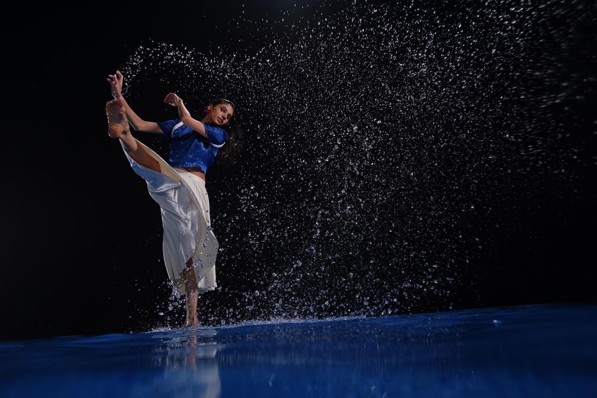 Female dancer, dancing in water, illuminated against a black background