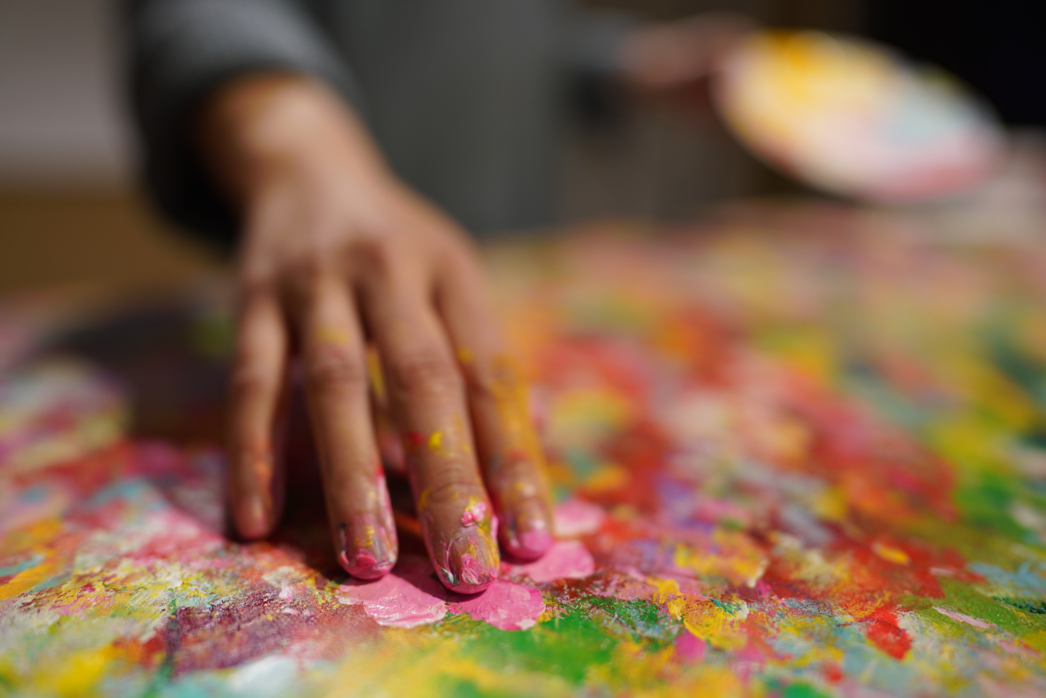 A hand with fingertips covered in paint in foreground