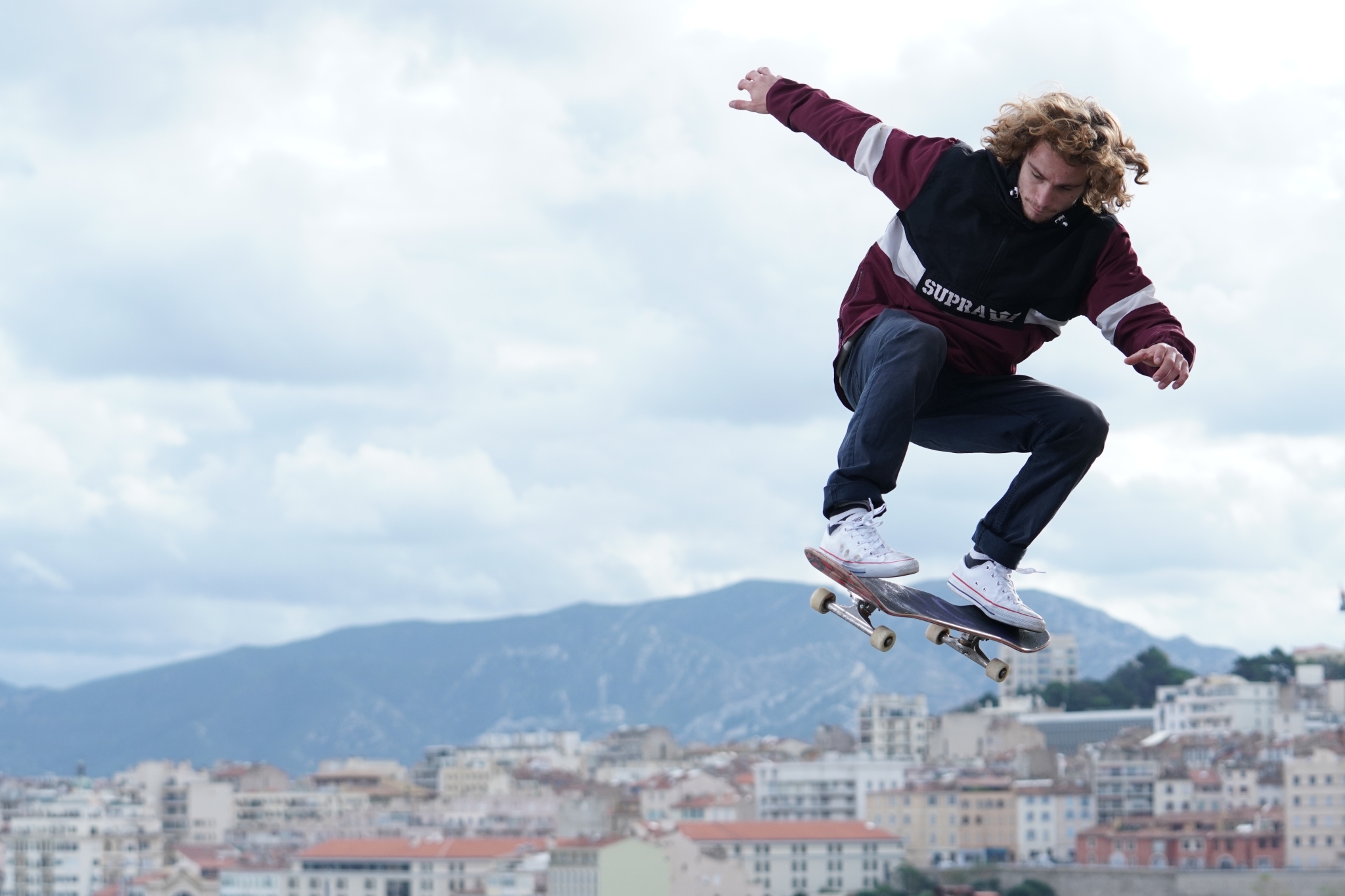A male skateboarder jump in the air with a cityscape in a bokeh background
