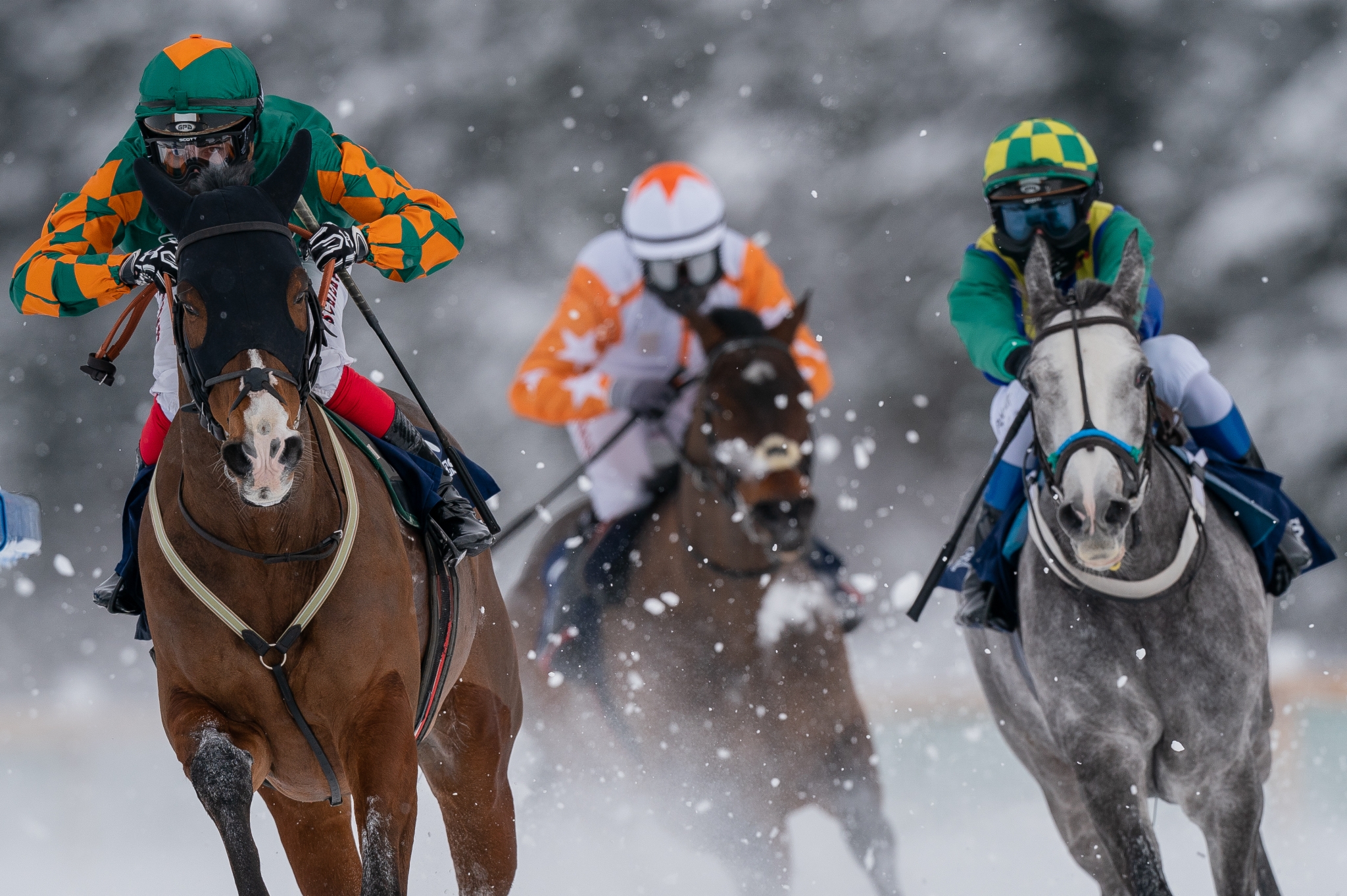 Riders on three horses galloping through snow
