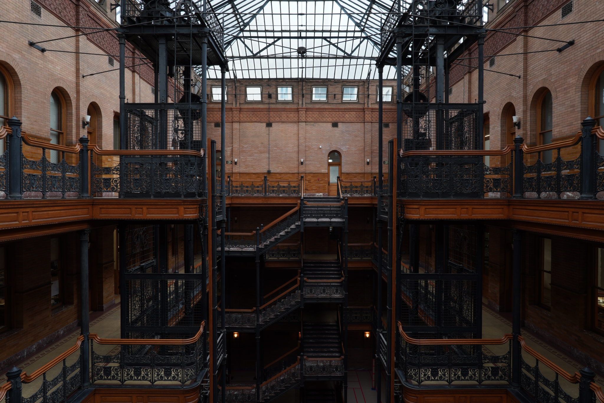 Central atrium of a multi-storey brick building with each floor connected by black metal staircases