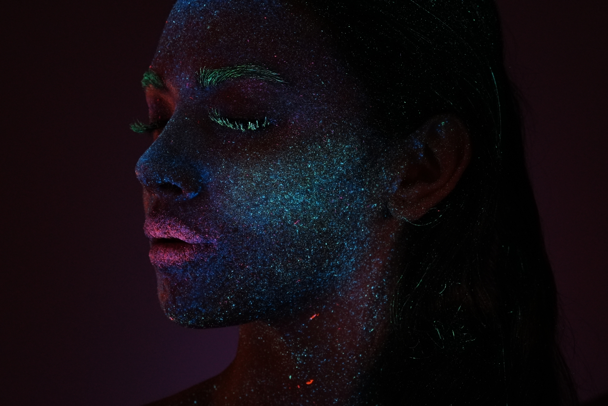 Close-up of a female face in the dark illuminated by luminescent make-up