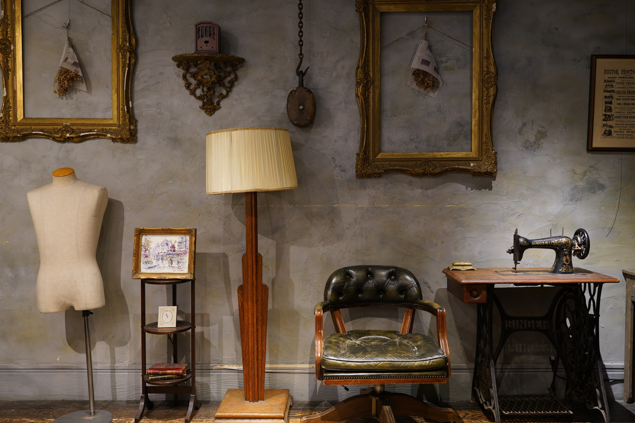 Collection of old-fashioned objects including picture frames, a lamp, a bust, and dark green leather chair