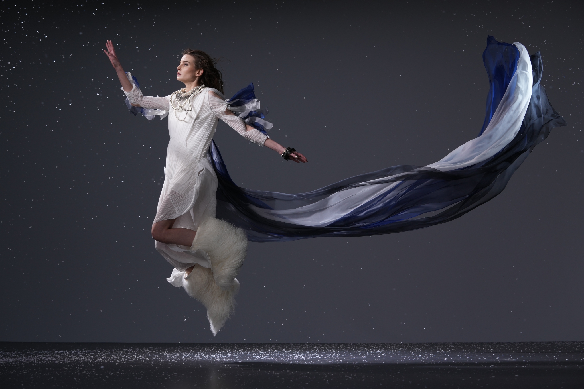 Female dancer jumping with blue cape billowing behind her
