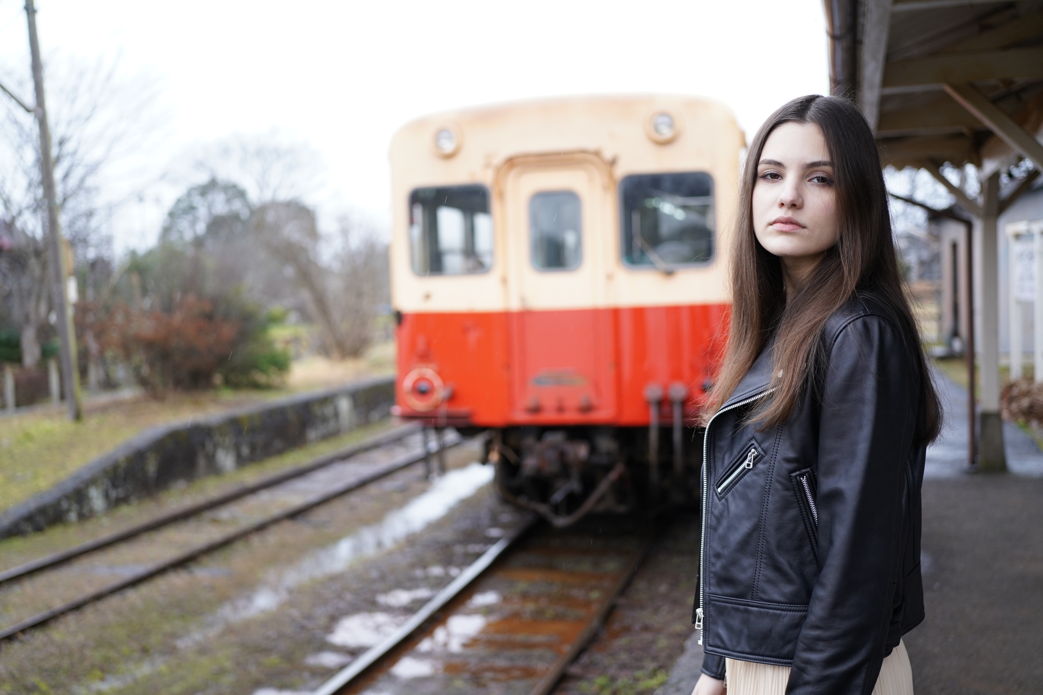 Female model stood next to train in bokeh background
