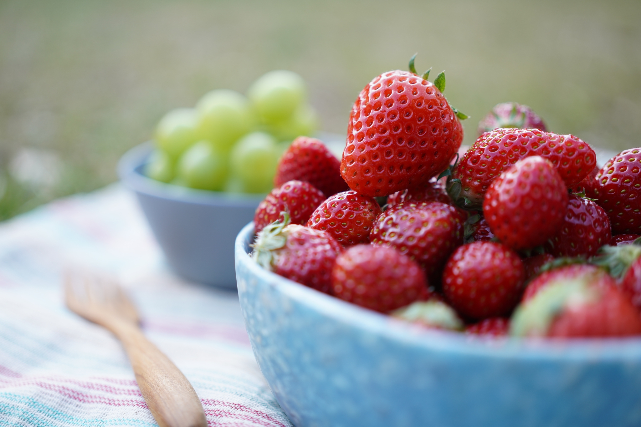 Bowl of strawberries with grapes in bokeh background