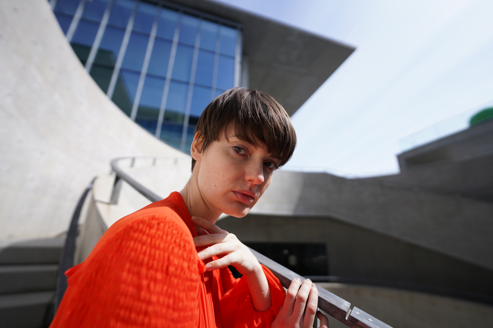 Portrait of female model in front of concrete and glass building