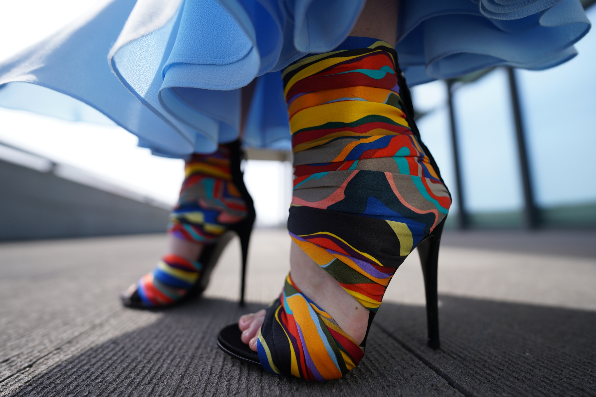 Close-up of a person's feet in multicoloured ankle boots stood on wooden boards