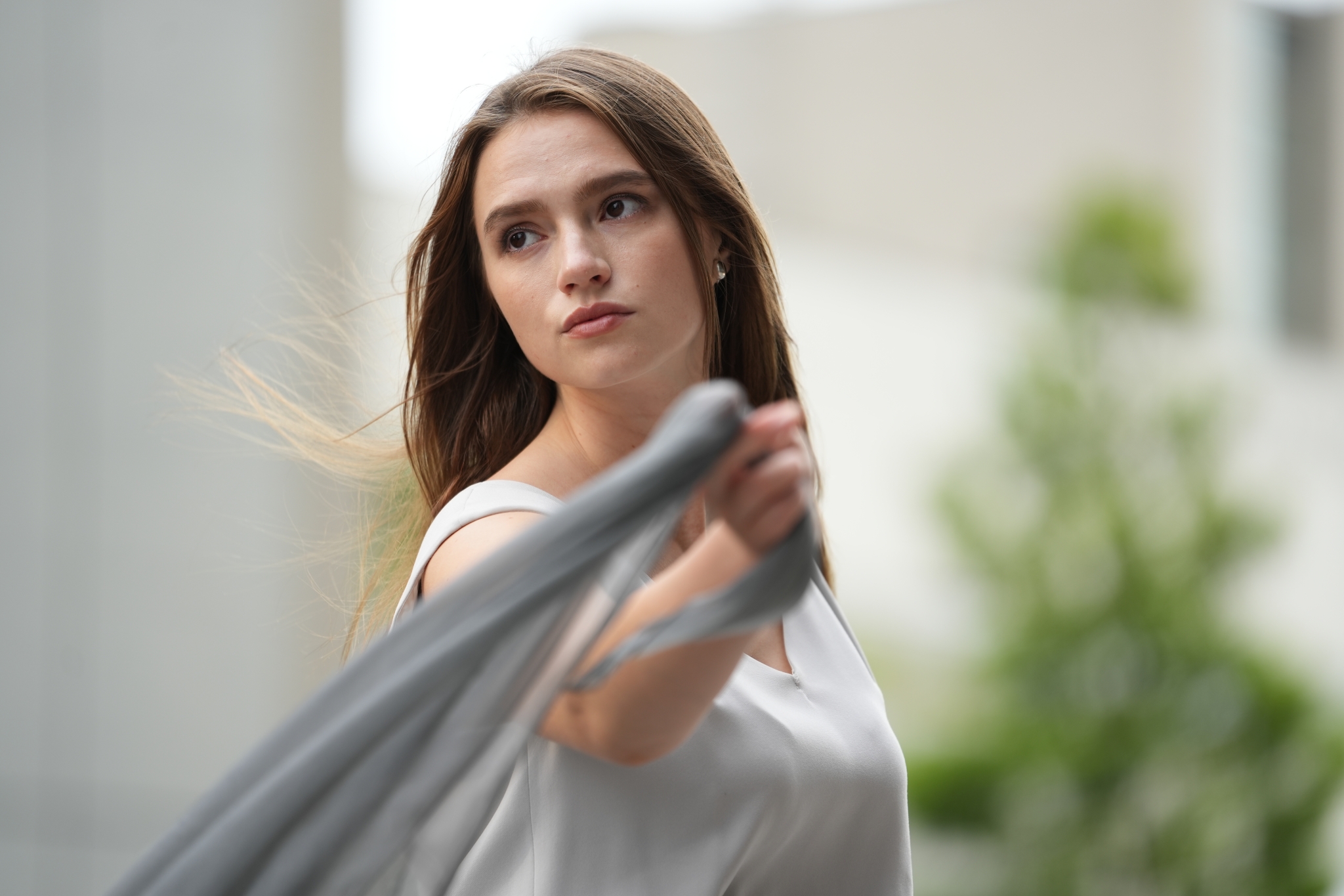 Female model holding a grey scarf with bokeh background