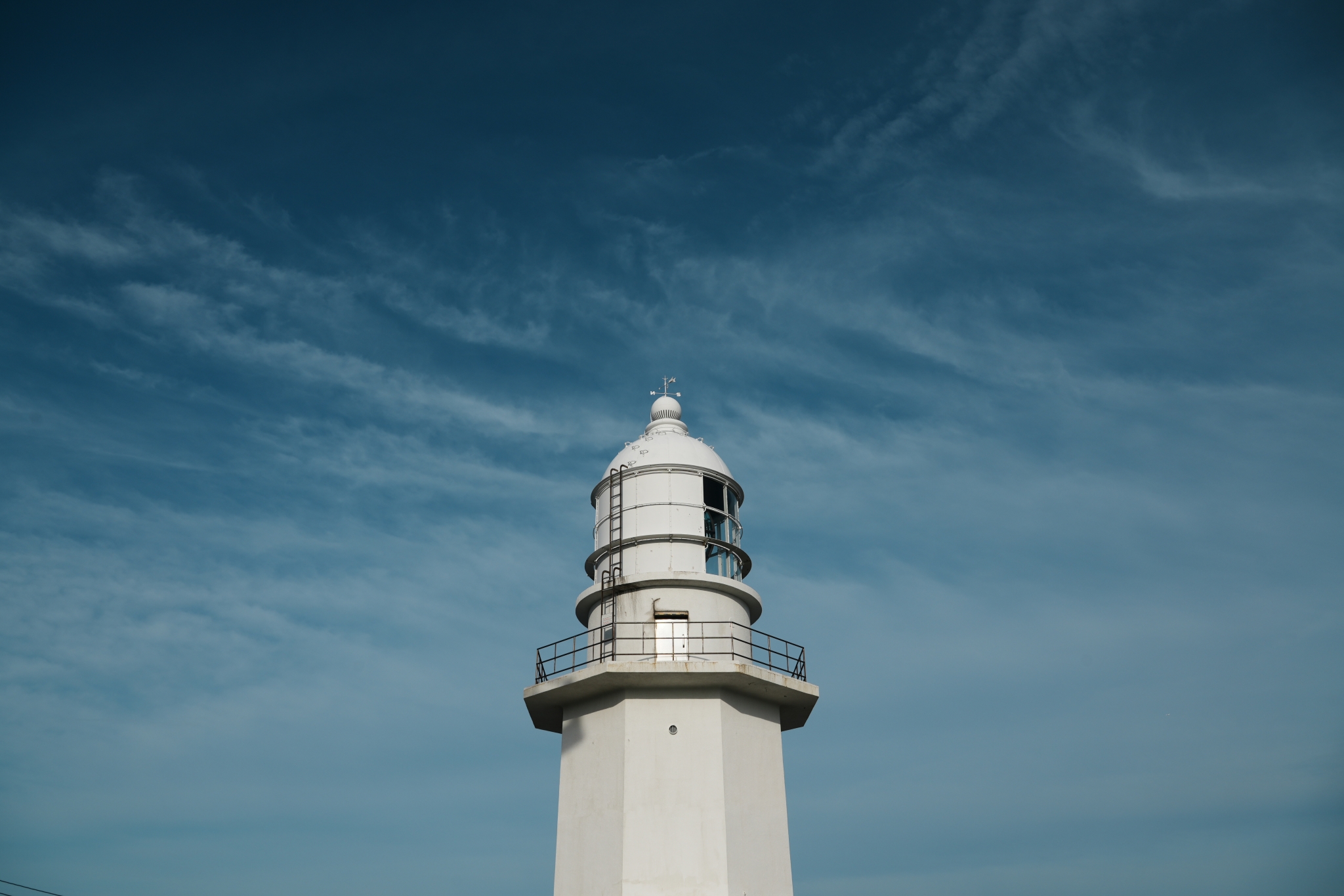 The top of a lighthouse set against a deep blue sky
