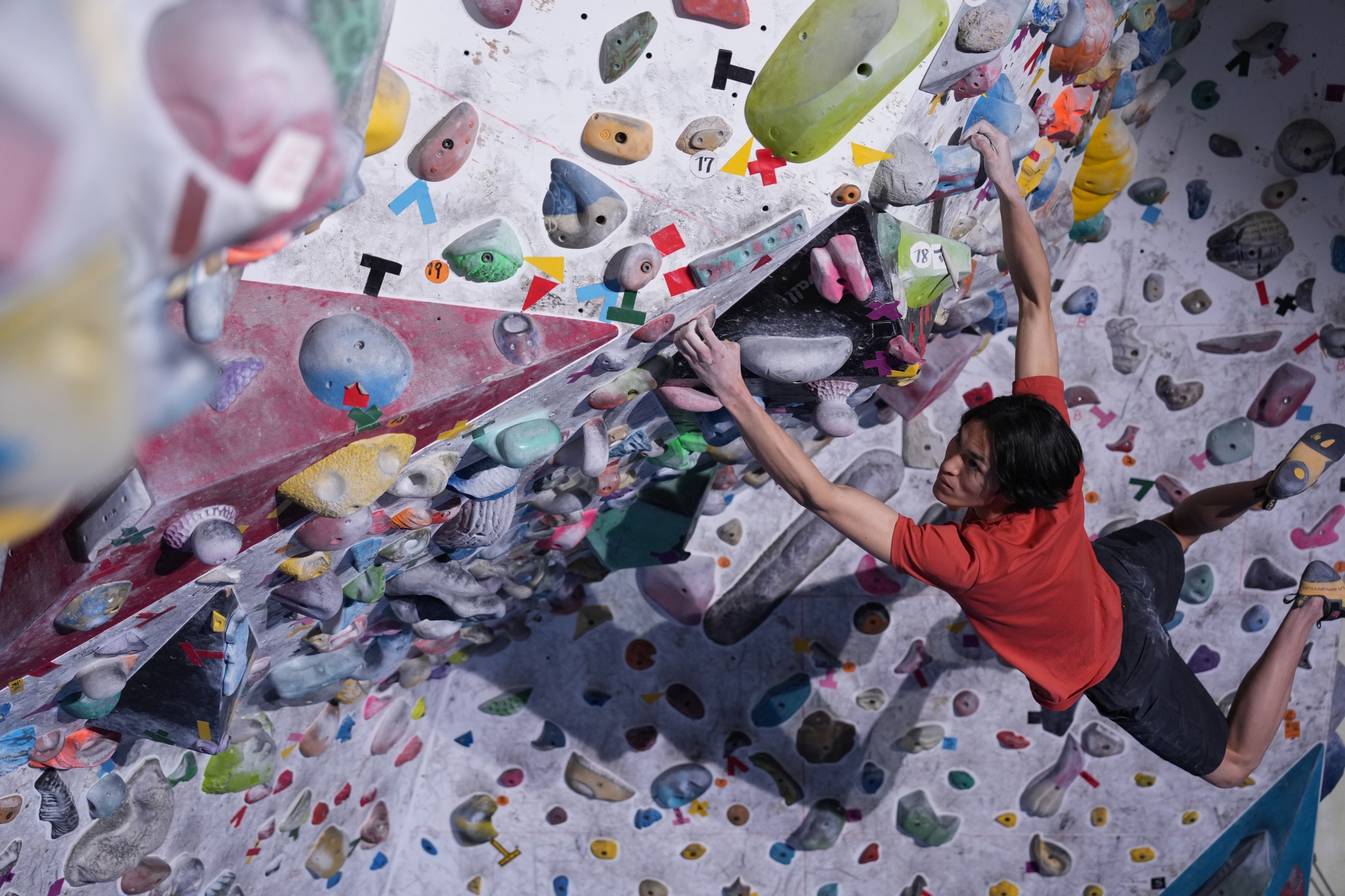 Man hanging by both arms from a wall in a bouldering gym