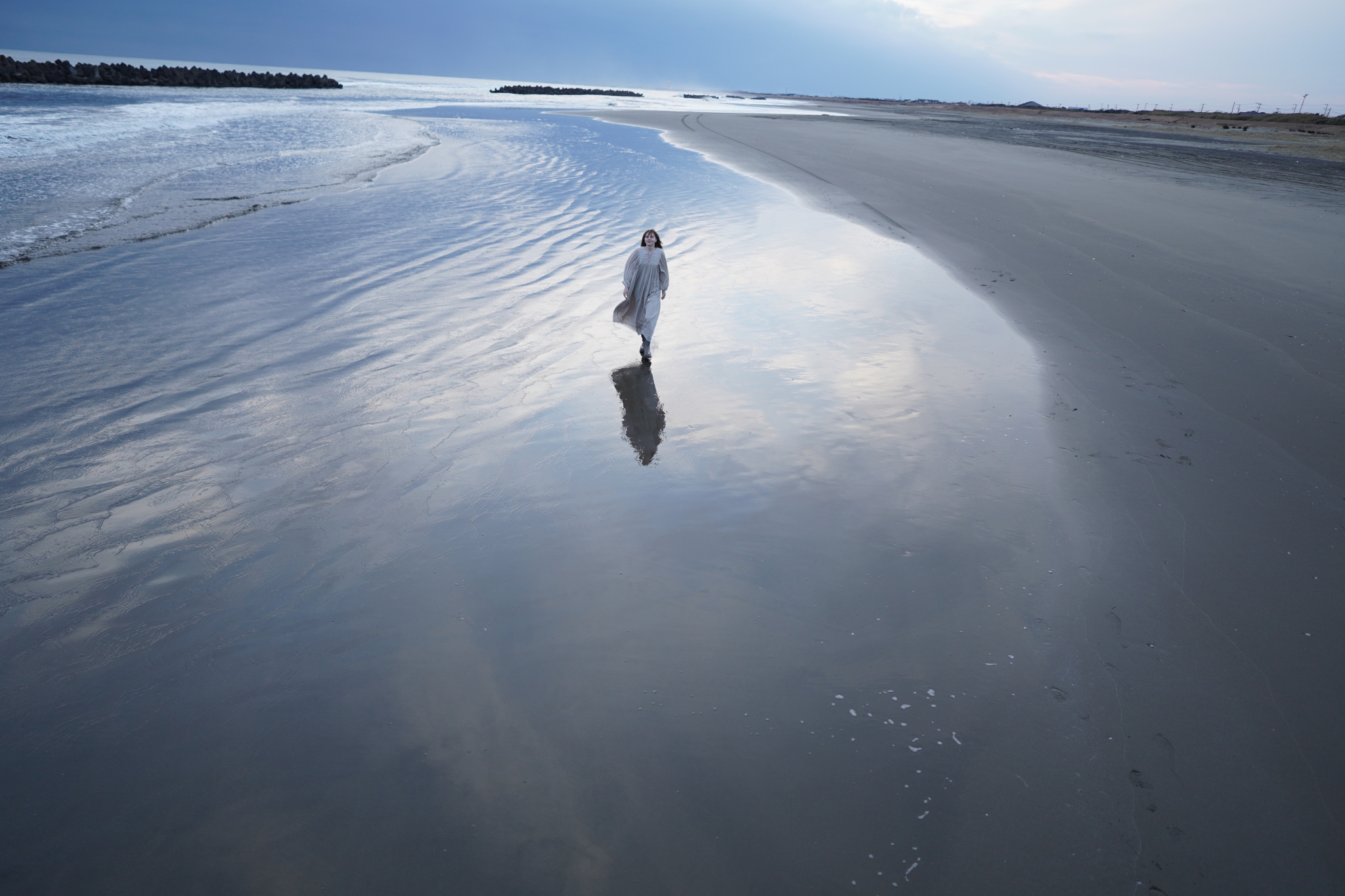 Landscape of a female model walking in shallow water along the beach at low ride