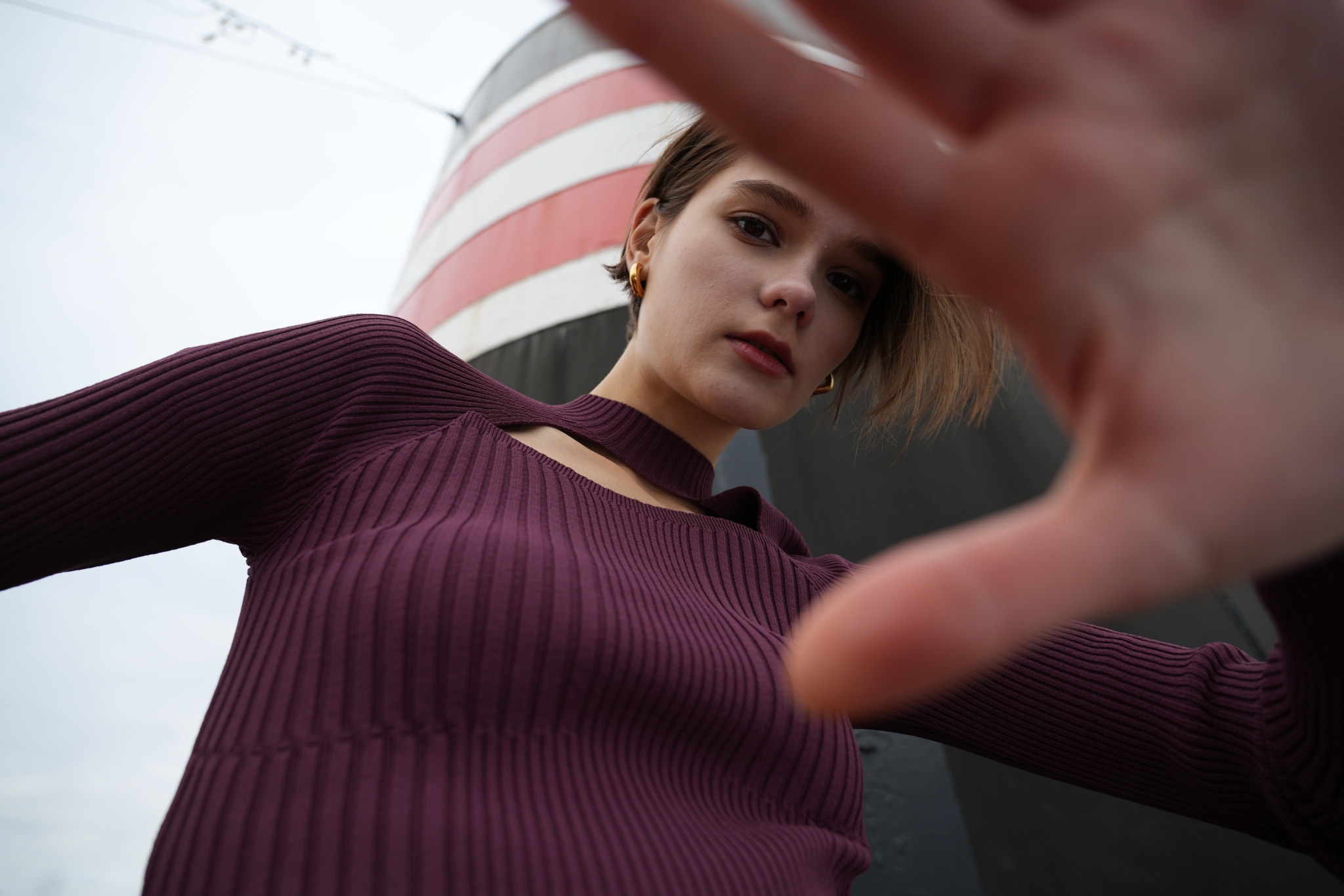 Upward shot of a female model, looking to camera and covering part of the shot with her hand