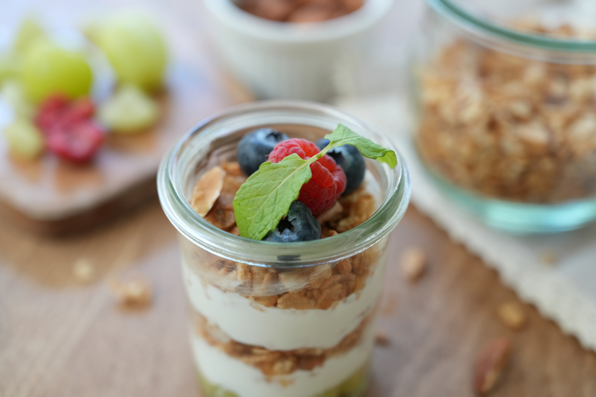 Muesli, fruit and yoghurt in a bowl with other bowls in bokeh background 