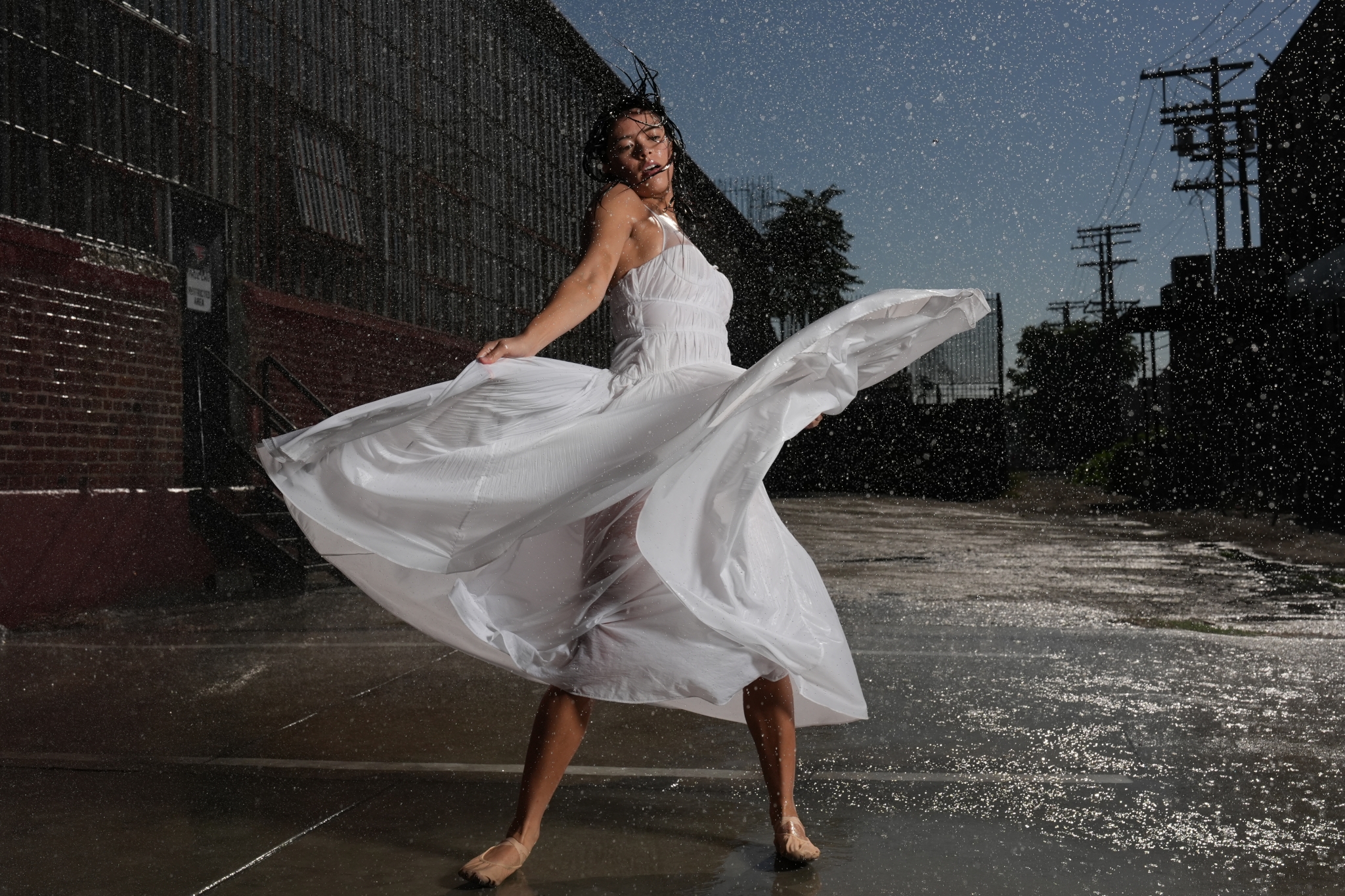 Female dancer in a white dress dancing in the rain, shot with flash synchronisation