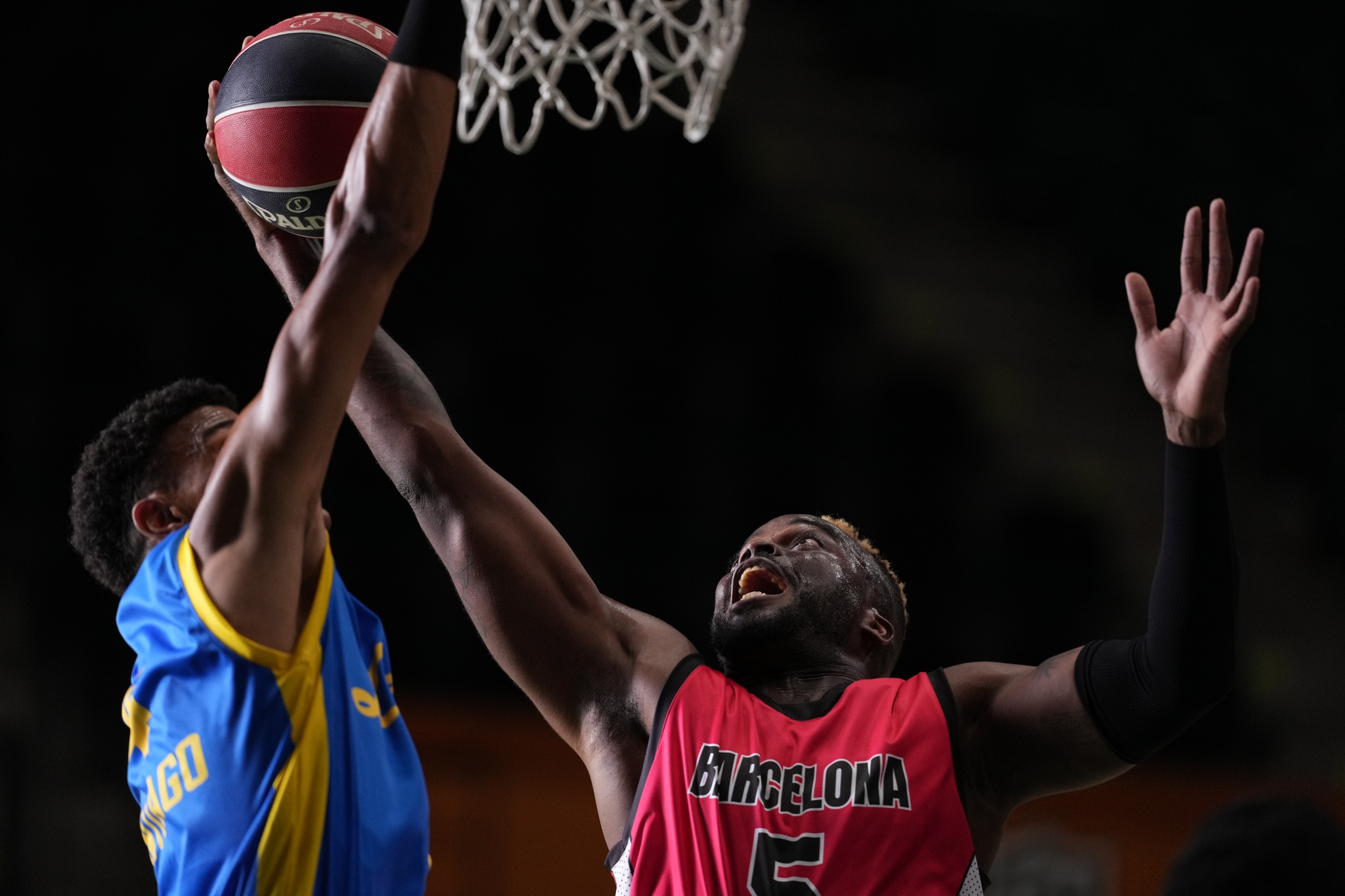 A basketball player tries to score a goal as another player defends