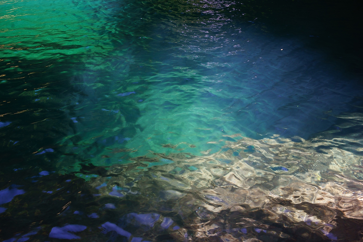 Shot of deep clear water pool with submerged rocks
