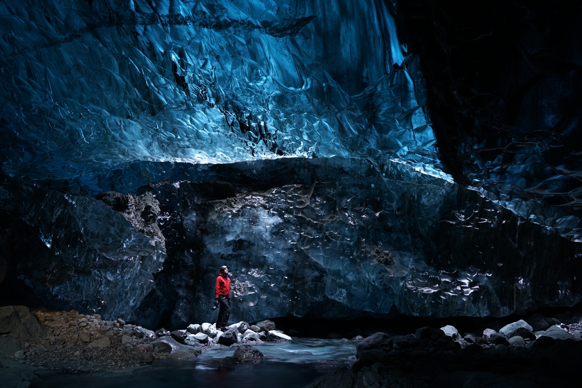 Man in ice cave with walls of ice in background
