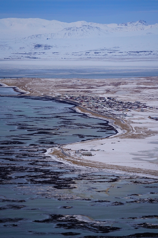 Aerial shot of coastline showing town and surrounding area with snow-covered mountains in background