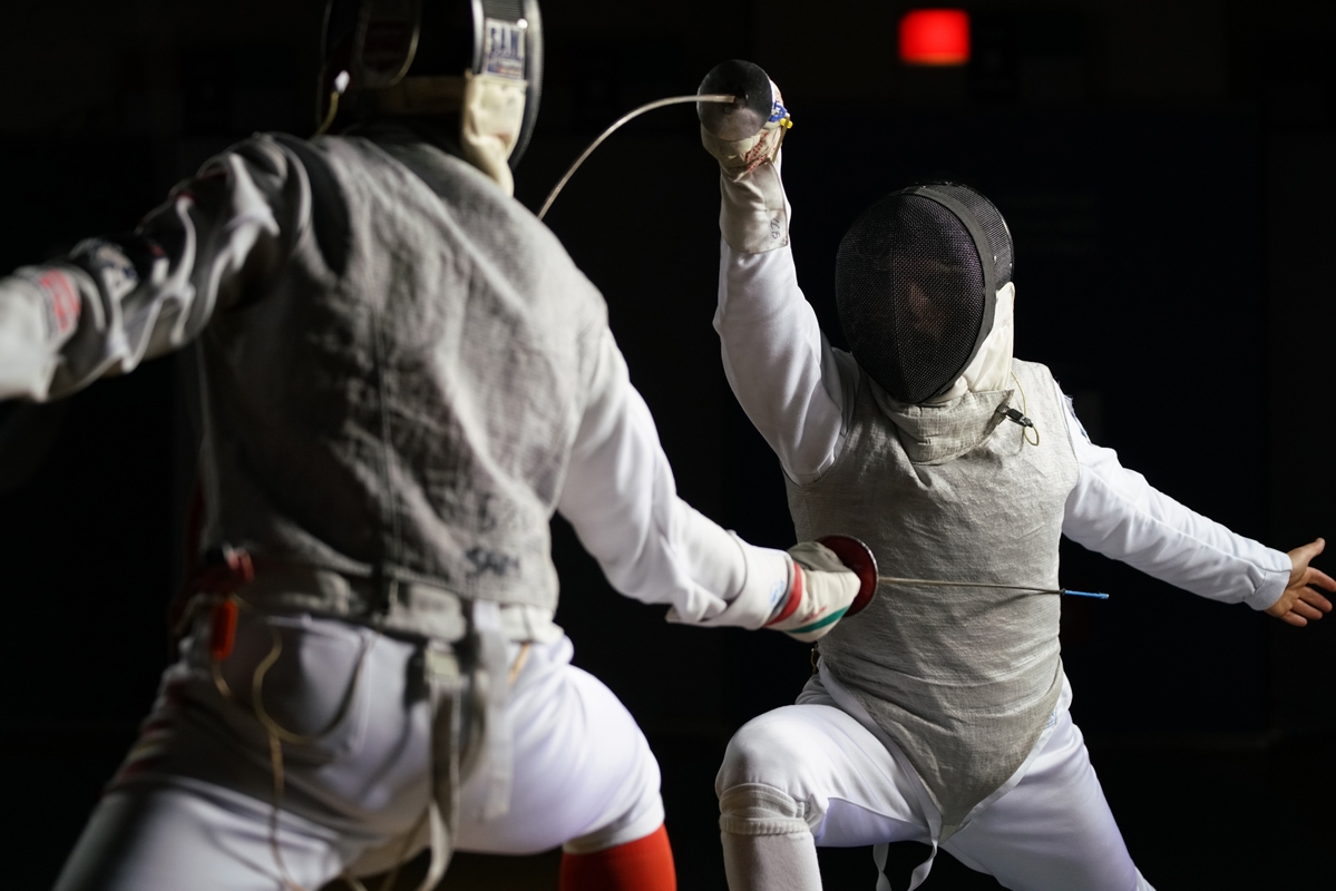 Two fencers in action, wearing masks