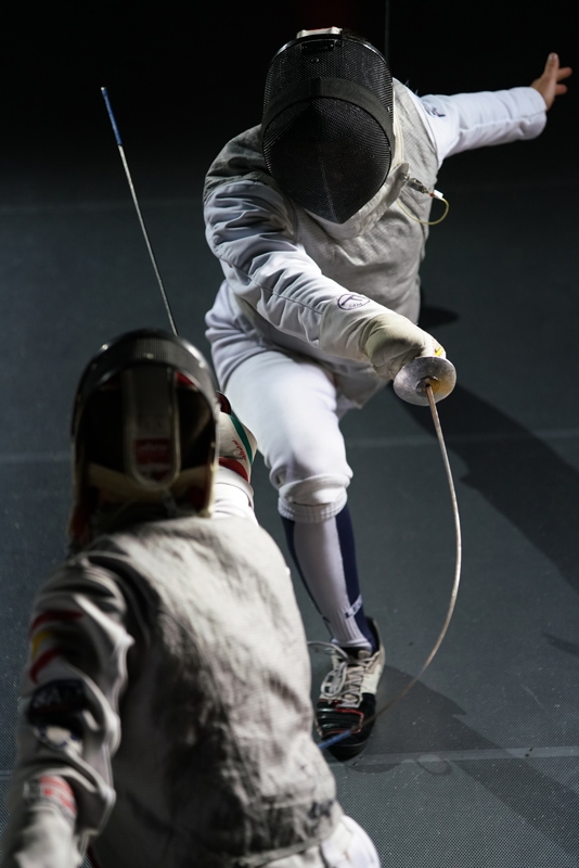 Two fencers in action, wearing masks