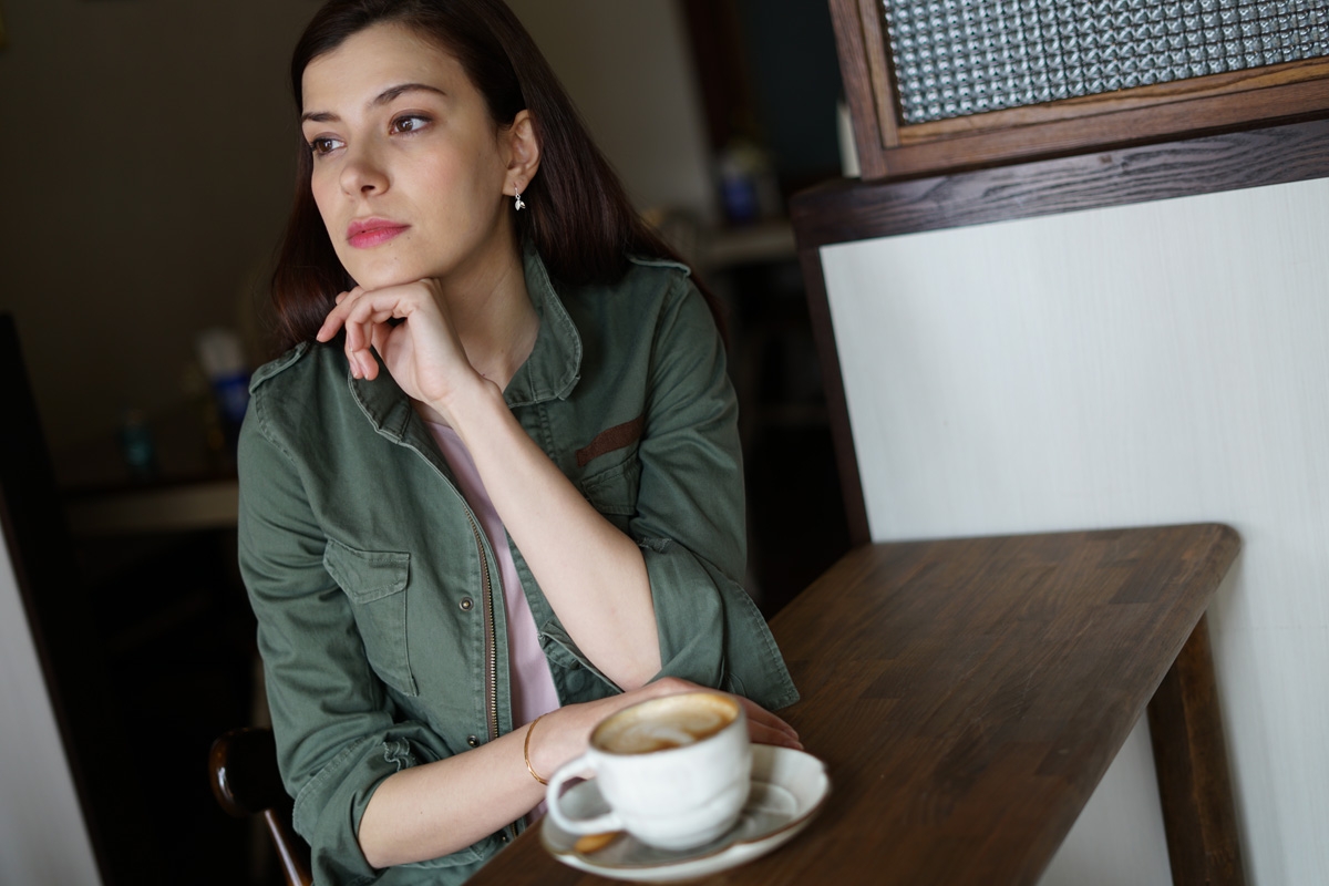 Portrait of woman leaning on table with coffee