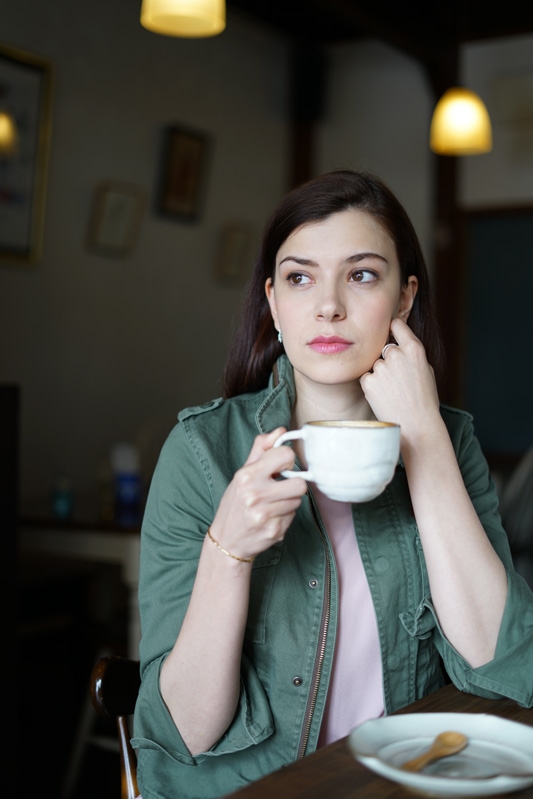 Portrait of woman holding coffee cup with dimly-lit indoor background