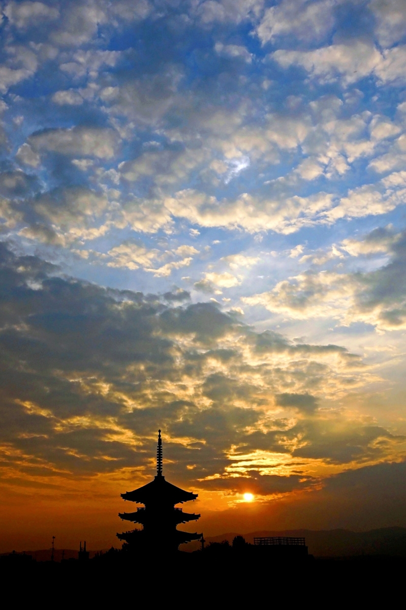 Temple pagoda silhouetted against red sky at sunset