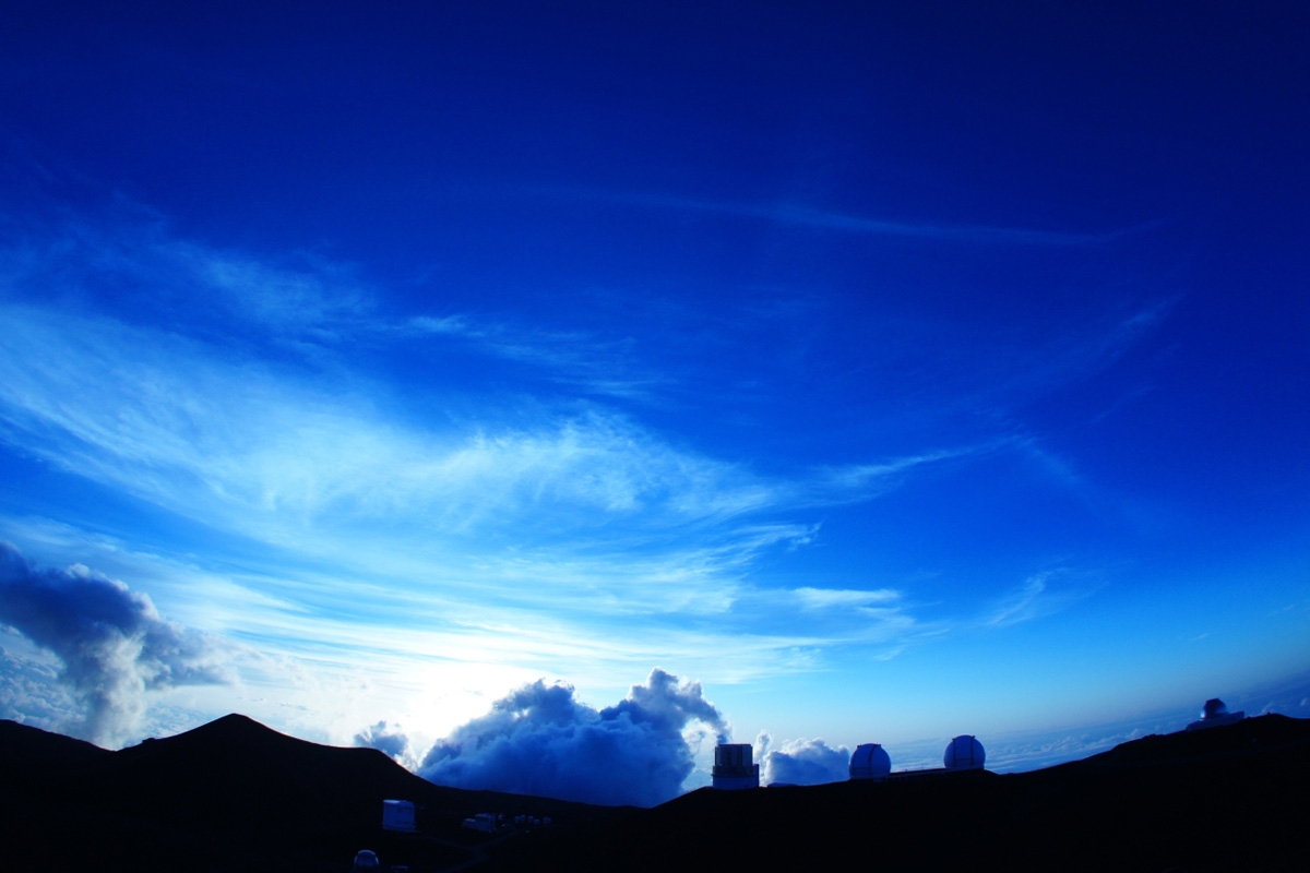 Mountain ridge with structures silhouetted against sky with low sun