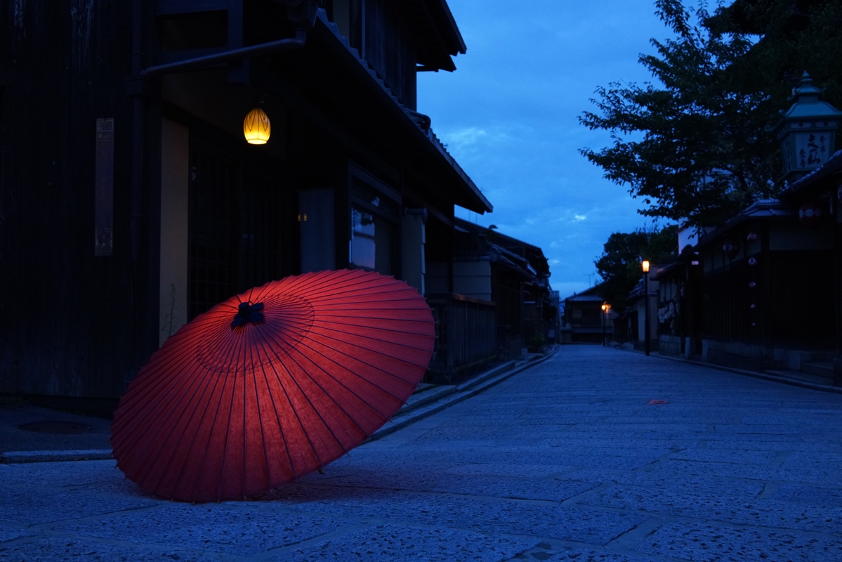 Ornamental red parasol lying on street in low light