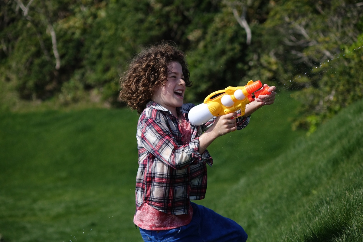 Profile portrait of boy shooting water pistol