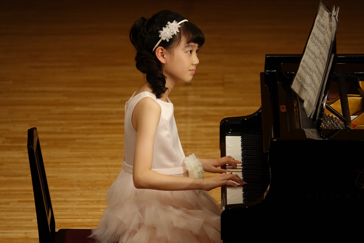 Girl playing grand piano looking at score