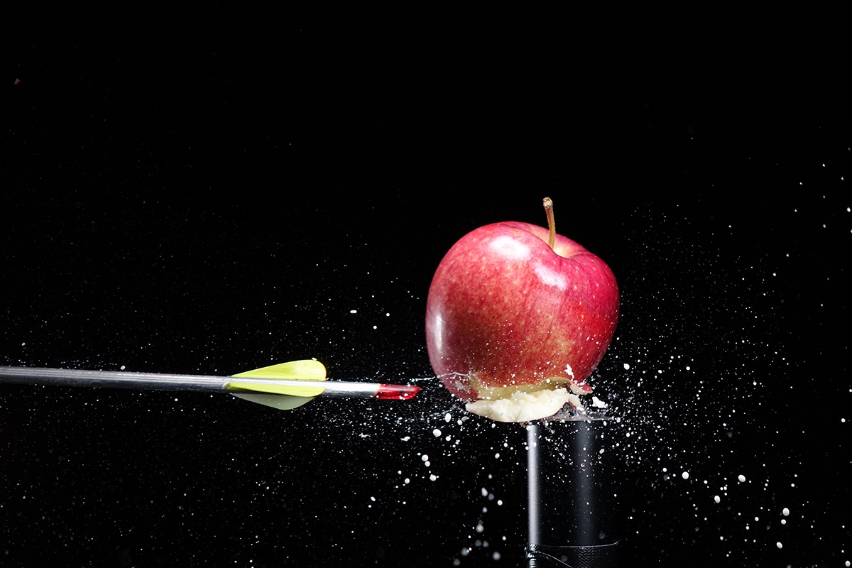 Shot showing an arrow in flight that has just passed through an apple