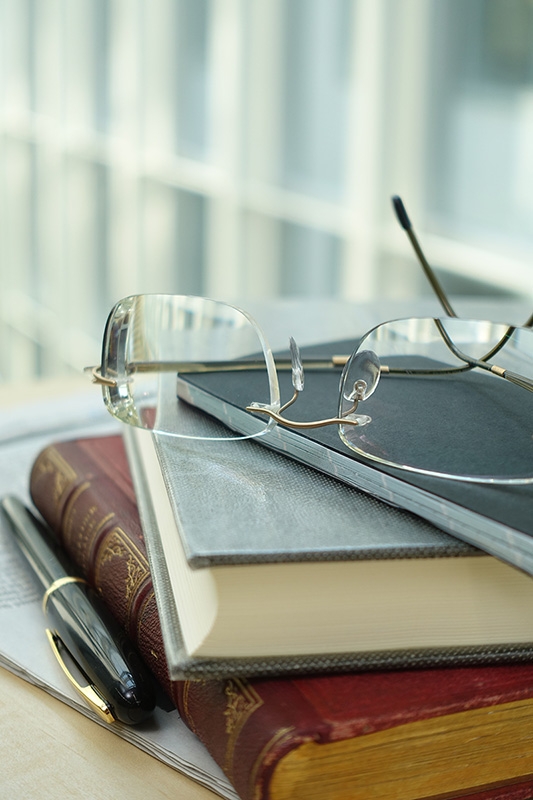 Close-up of glasses on books with pen