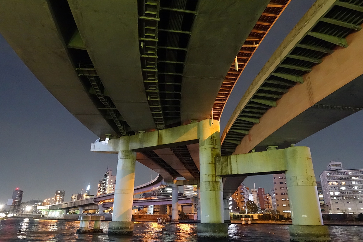 Nocturnal shot from beneath expressway bridge over water with city background