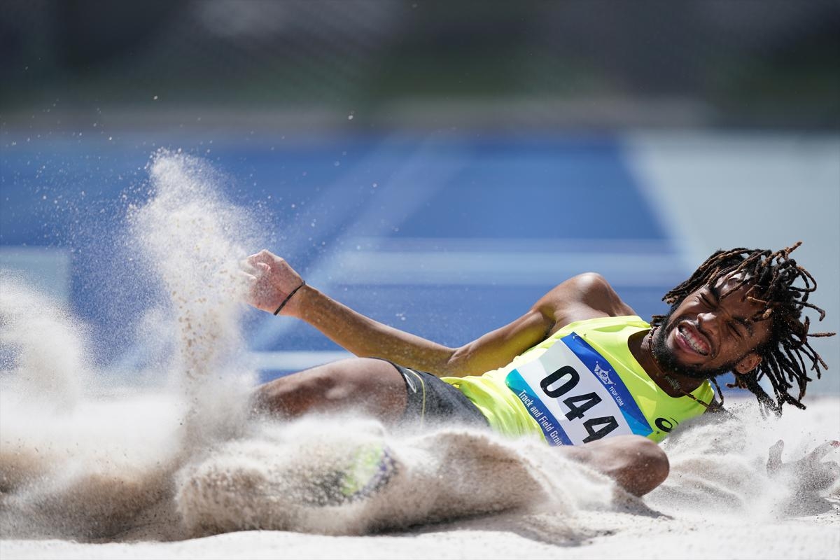 Competition jumper landing in sand pit throwing sand up