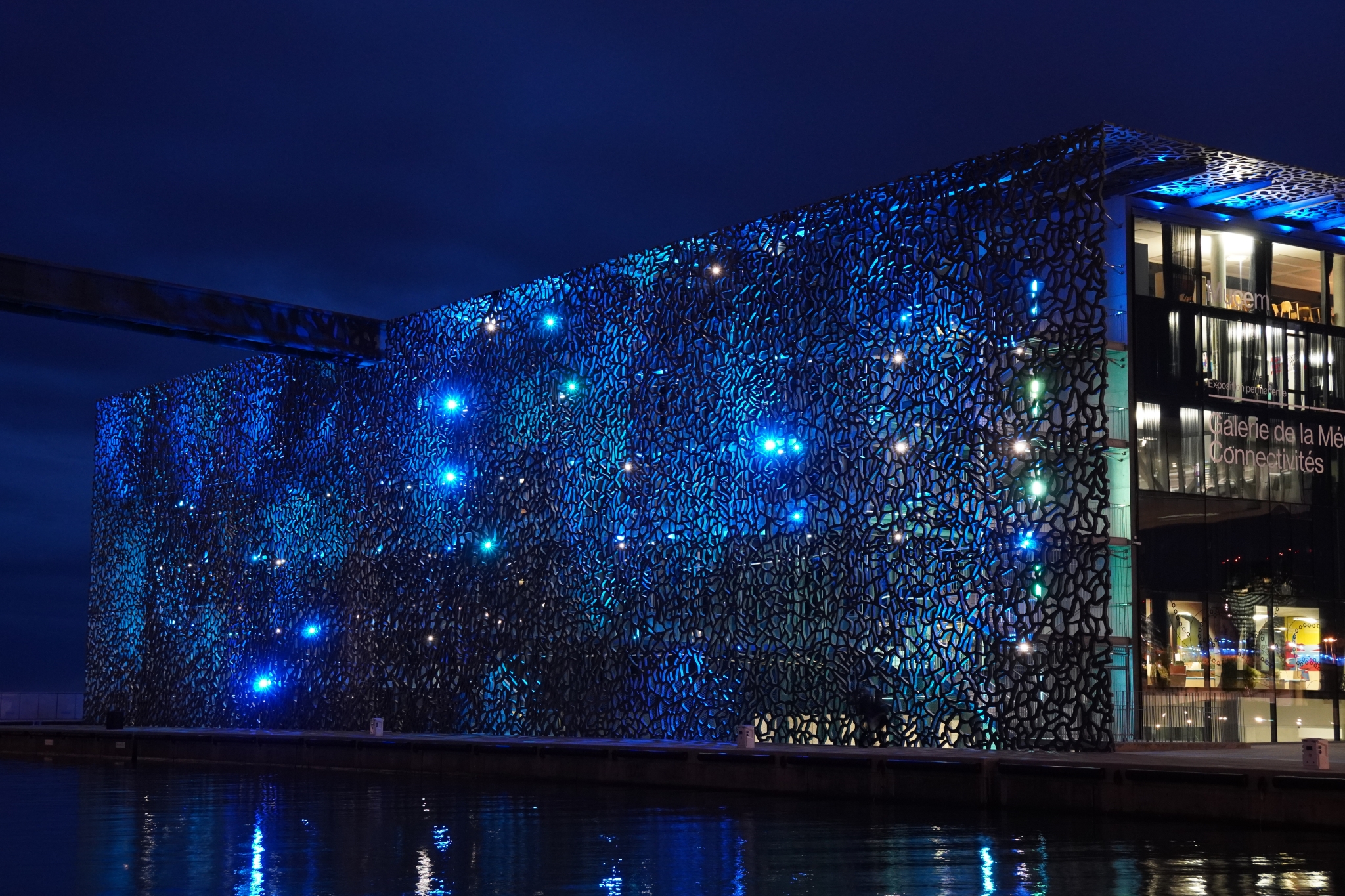 Glass building illuminated at night with city lights reflected